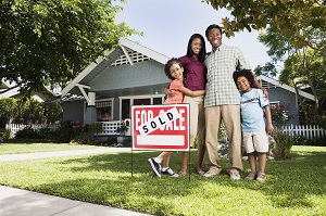 family standing next to sold sign outside the house